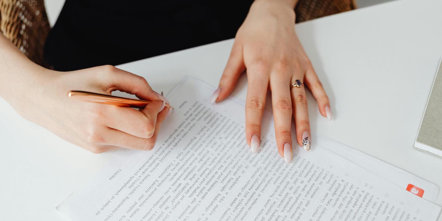 Person Holding Pen Writing on a Document