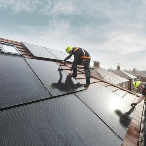 An engineer fits a solar panel to the roof of a house