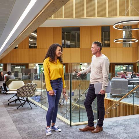 Two members of staff stand chatting inside the Nexus innovation hub at Leeds University