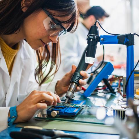 A female student soldering in an electronics class