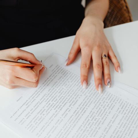 Person Holding Pen Writing on a Document