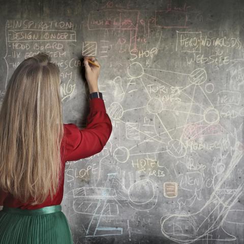 Woman in Red Long Sleeve Writing On Chalk Board