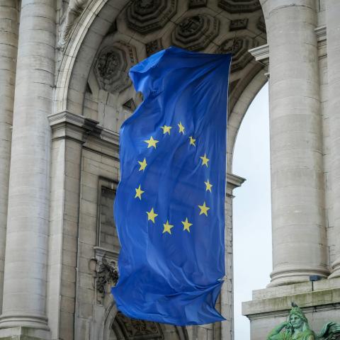 The flag of the European Union hangs beneath a stone archway