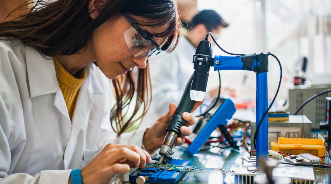 A female student soldering in an electronics class