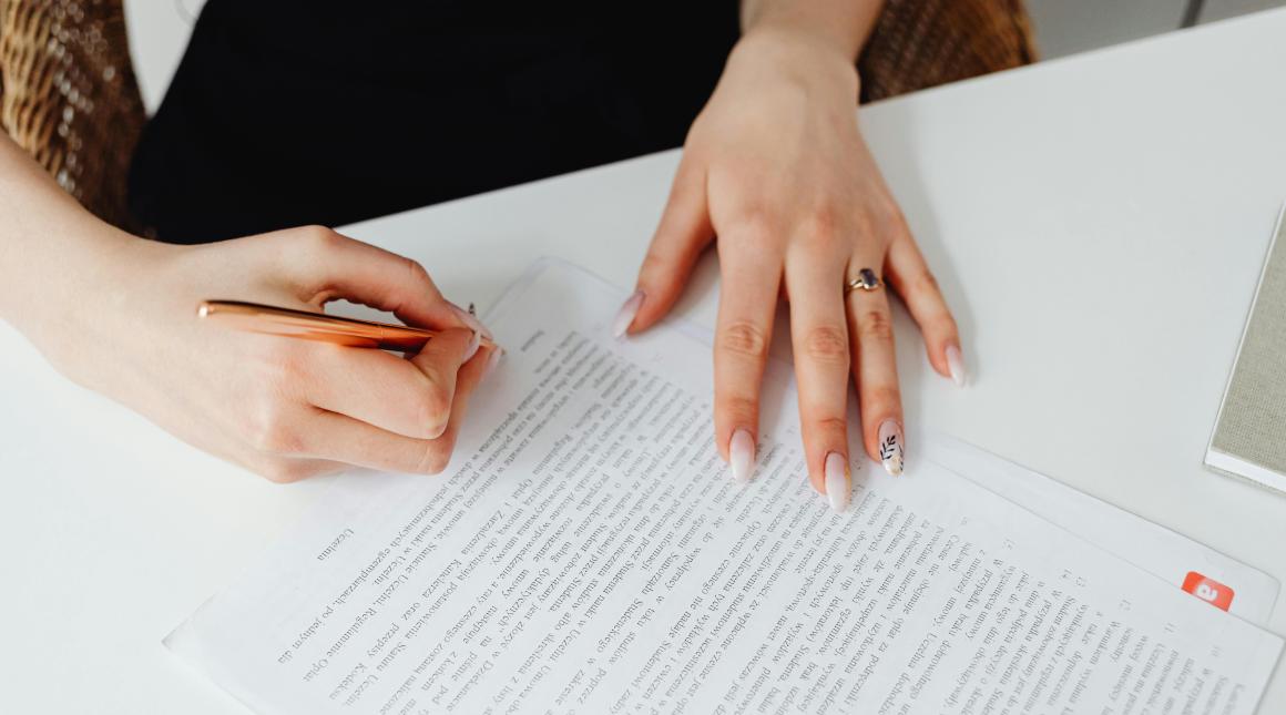 Person Holding Pen Writing on a Document