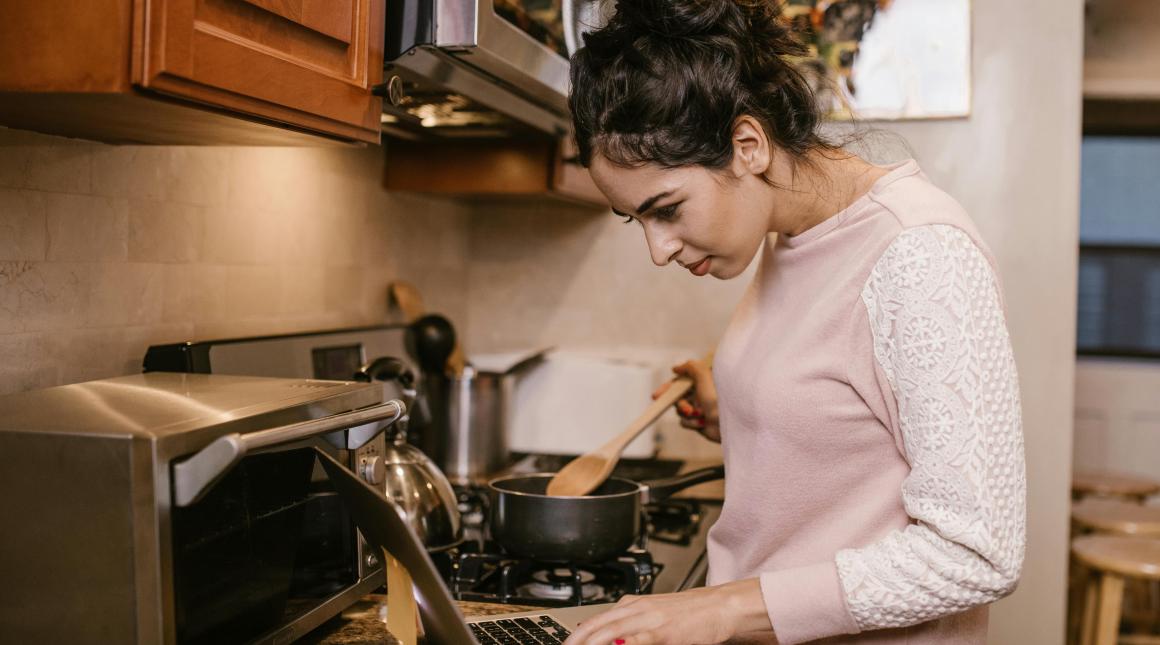 Student works on laptop while cooking