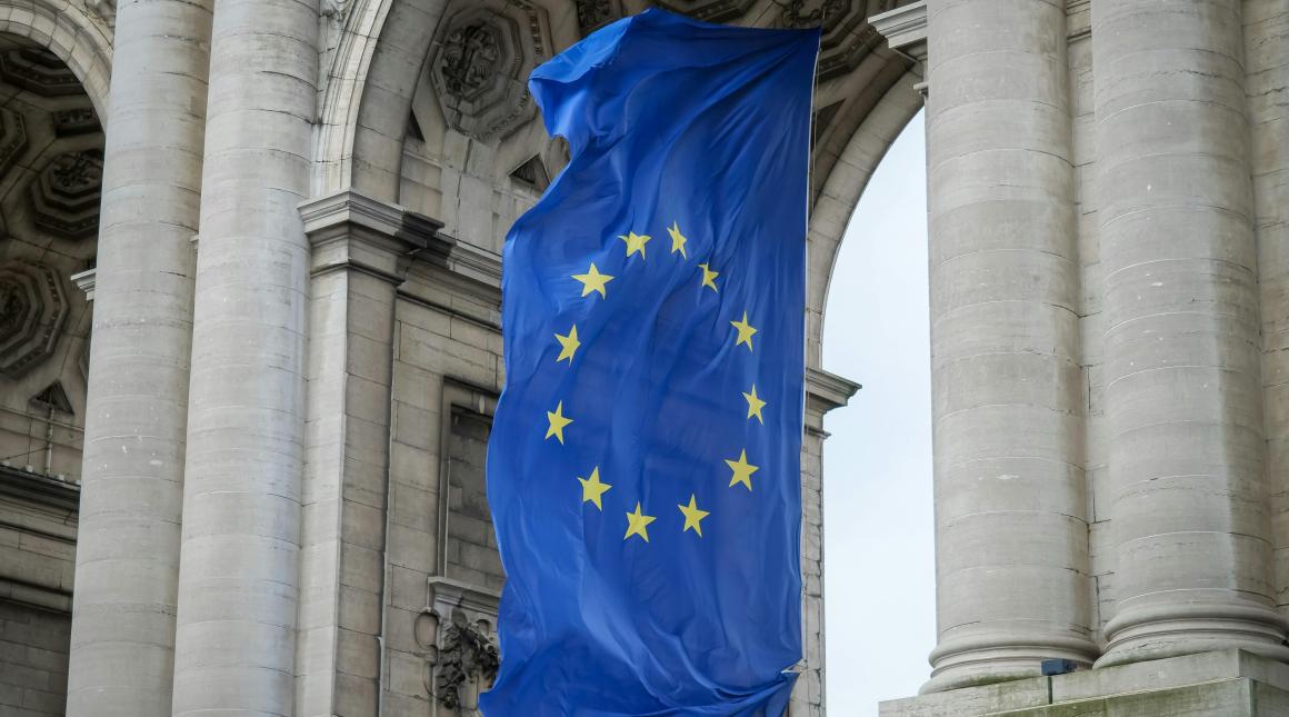 The flag of the European Union hangs beneath a stone archway