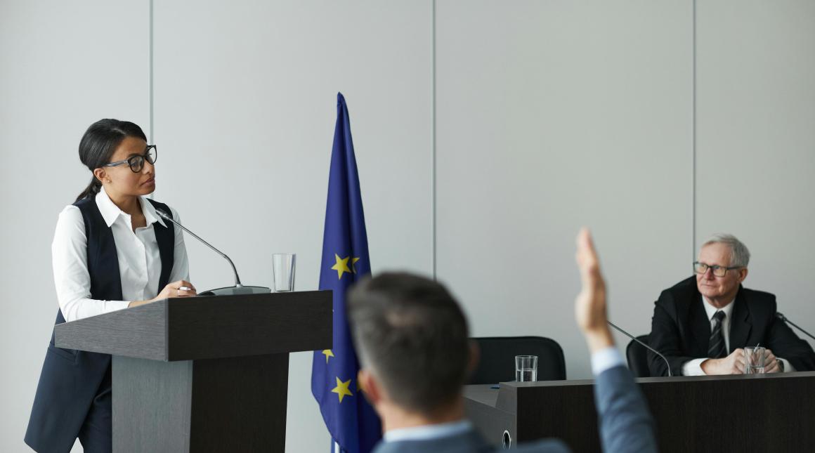 Woman Standing at a Rostrum and Talking during a Political Conference