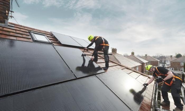 An engineer fits a solar panel to the roof of a house