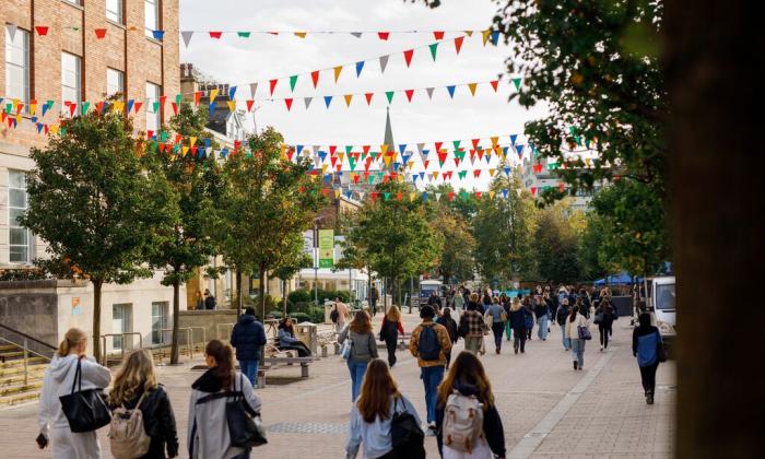 A busy pedestrianised street with groups of students on the University of Leeds campus