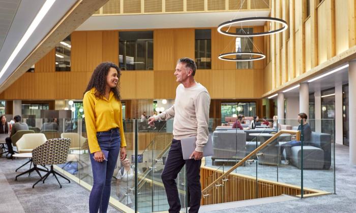 Two members of staff stand chatting inside the Nexus innovation hub at Leeds University