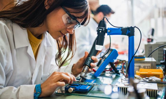 A female student soldering in an electronics class