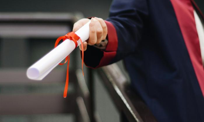 A hand of a graduating student holding a degree scroll