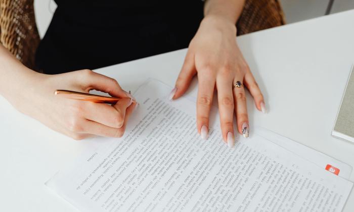 Person Holding Pen Writing on a Document