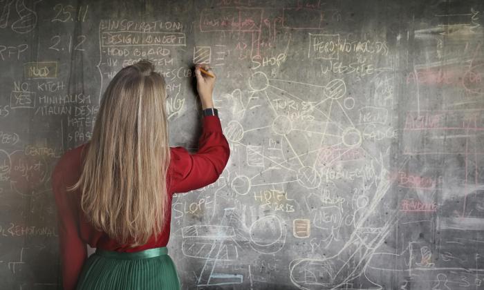 Woman in Red Long Sleeve Writing On Chalk Board