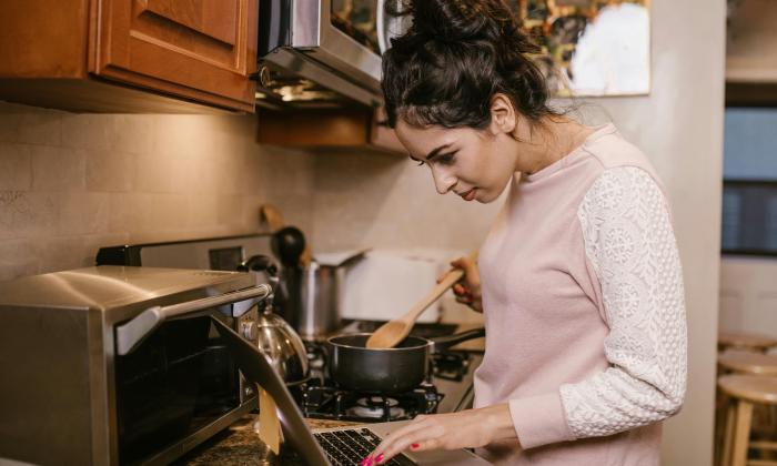 Student works on laptop while cooking