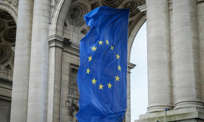 The flag of the European Union hangs beneath a stone archway