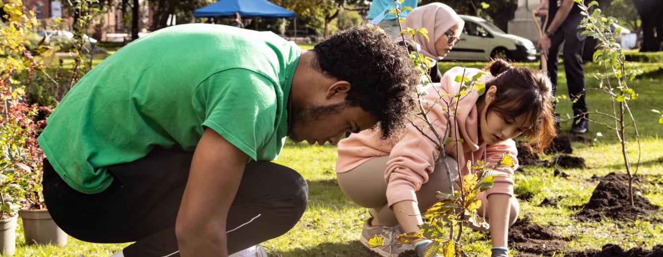 Two people plant trees to create green space in the Ardwick area of Manchester