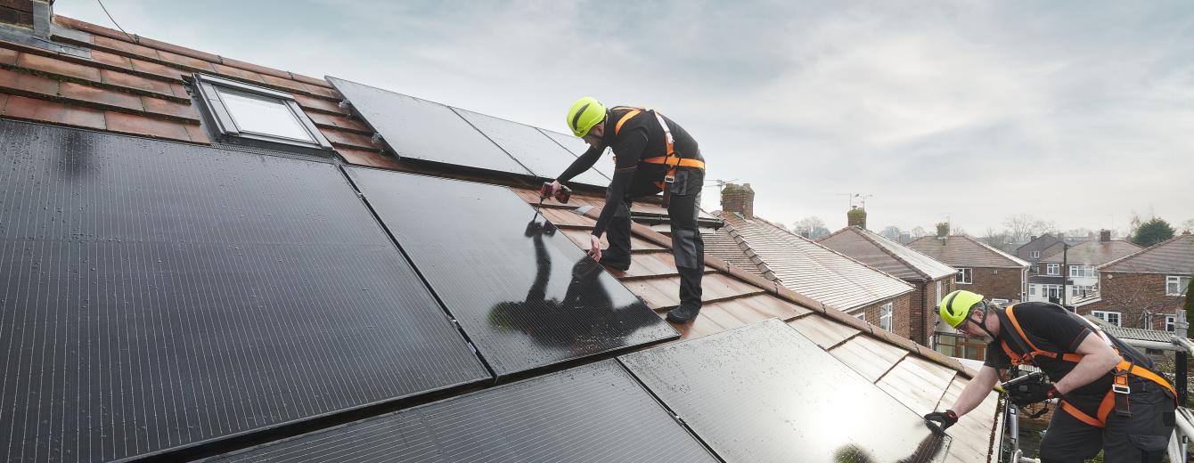 An engineer fits a solar panel to the roof of a house