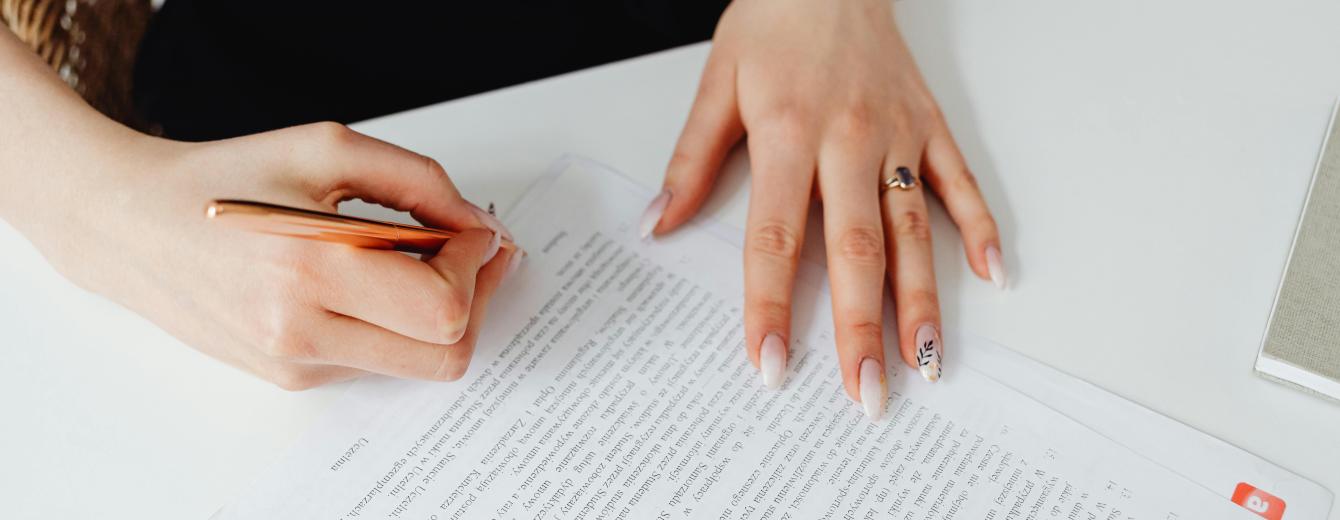 Person Holding Pen Writing on a Document